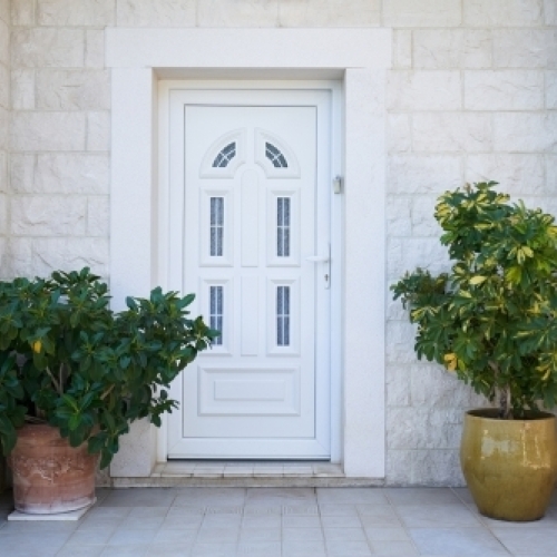 Hvid PVC plastdør med vinduesfelter monteret i husfacade